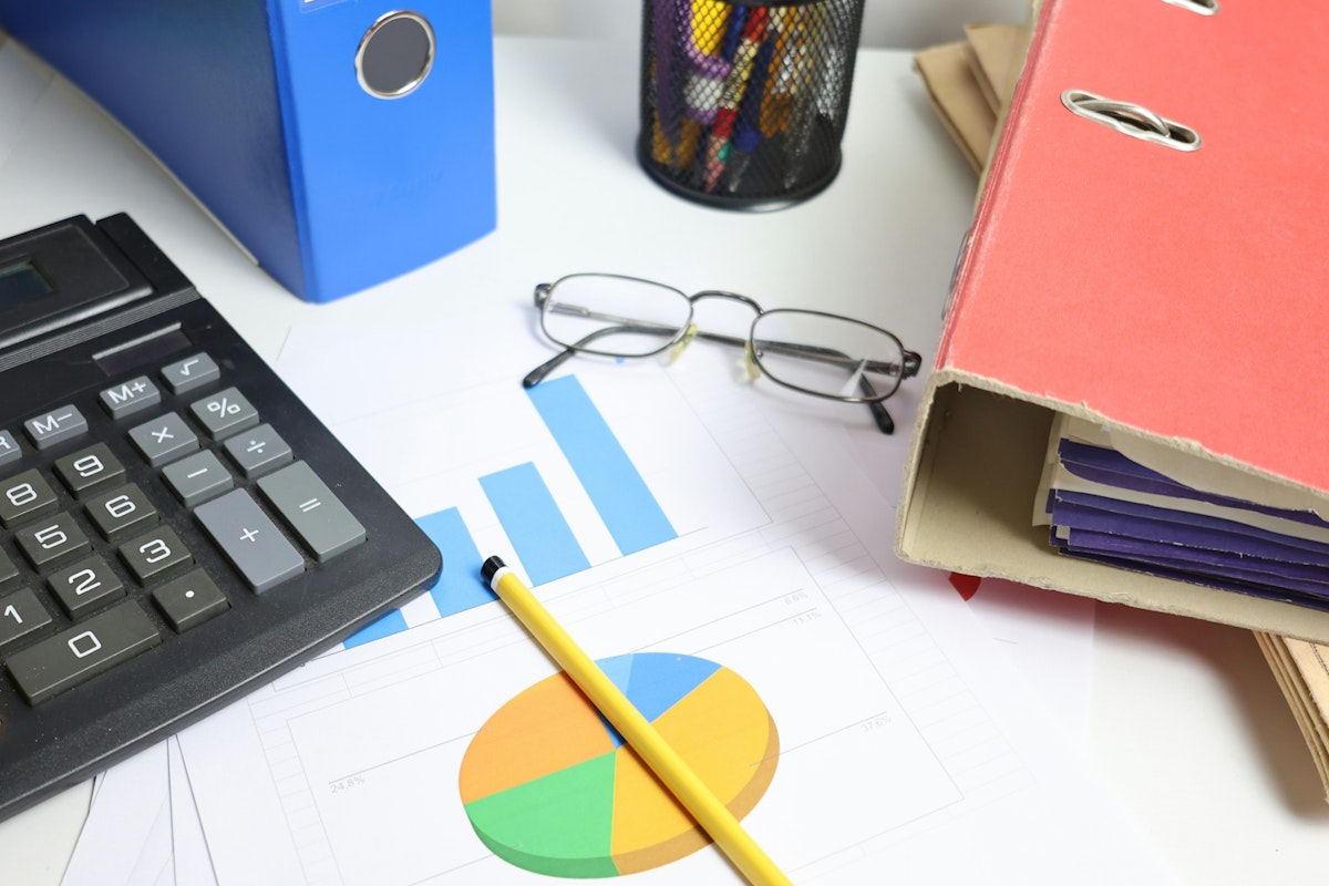 4p2xZdIhXkGulMfaVlAcKX-desk-with-calculator-charts-and-binders-FVwy7PBiSUo